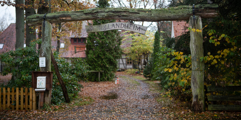 Zufahrt zu enem Grundstück, darüber ein Holzmast mit einem Kolzschild mit der Beschriftung "Schullandheim"