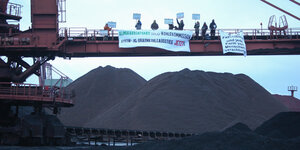 Umweltaktivisten protestieren vor einem Haufen Steinkohle
