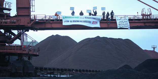 Umweltaktivisten protestieren vor einem Haufen Steinkohle