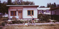 Ein Junge mäht Rasen vor einem kleinen Wochenendehaus, Datsche genannt, ein Foto aus dem Jahr 1968