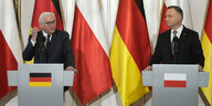 Zwei Männer vor der deutschen und polnischen Flagge stehen hinter Pulten