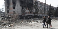 Zwei Frauen gehen in der Nähe von beschädigten Gebäuden in Mariupol entlang
