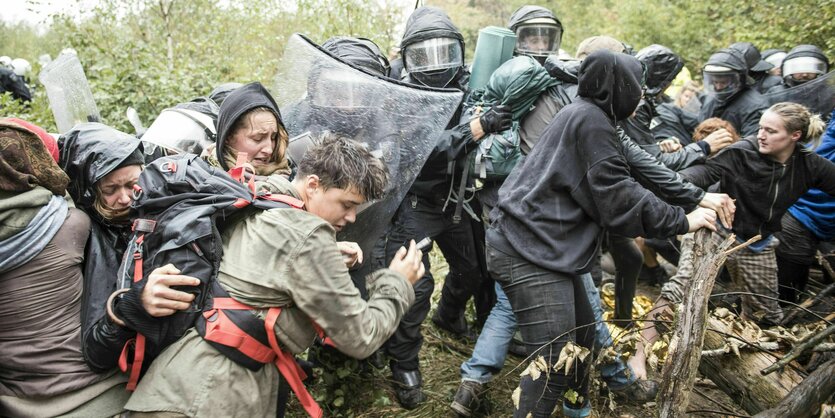 Ein Durcheinander von Menschen im Wald, junge Menschen, weinende Gesichter, es regnet, dazwischen Polizei