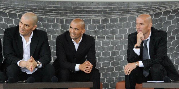 Die drei Zidane-Brüder sitzen nebeneinander auf einer Veranstatlung