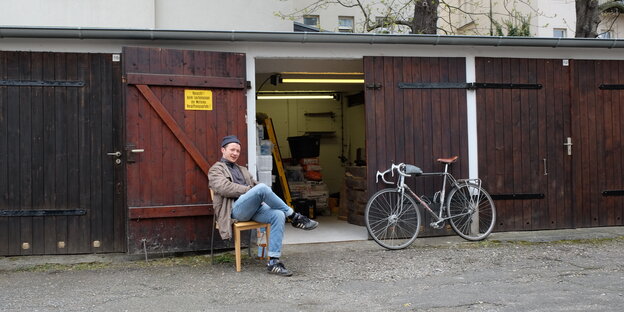Ein junger Mann sitzt vor einer offenen Garage in Leipzig