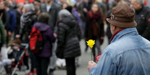 Beim Ostermarsch in Hamburg 2016 hält ein Mann eine Osterglocke in der Hand