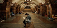 Eine Frau liest ein Buch in der U-Bahnstation von Charkiw