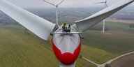 Zwei Personen in Warnwesten warten in luftiger Höhe eine Windenergieanlage