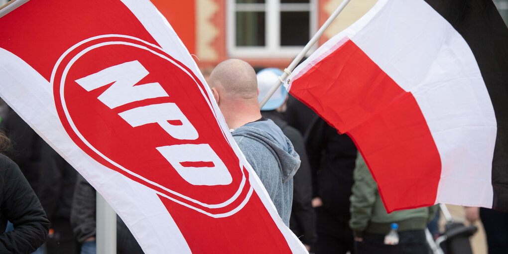 Glatzkopf zwischen Fahnen der NPD und des Deutschen Reichs