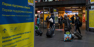 Ein Plakat mit Informationen für die aus der Ukraine ankommenden Flüchtlinge hängt in der Bahnhofshalle am Hauptbahnhof, während im Hintergrund Reisende vorbeigehen