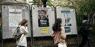 Teenager laufen an zerrissenen Wahlkampfplakaten vorbei