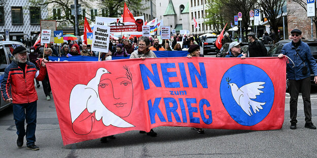 Menschen tragen ein großes Banner vor sich her mit der Aufschrift Nie wieder Krieg