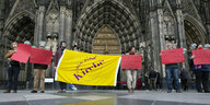 Menschen mit Bannern und Plakaten vor dem Eingangsportal des Kölner Doms
