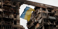 Eine ukrainische Flagge hängt zwischen zwei zerstörten Gebäuden in Mariupol