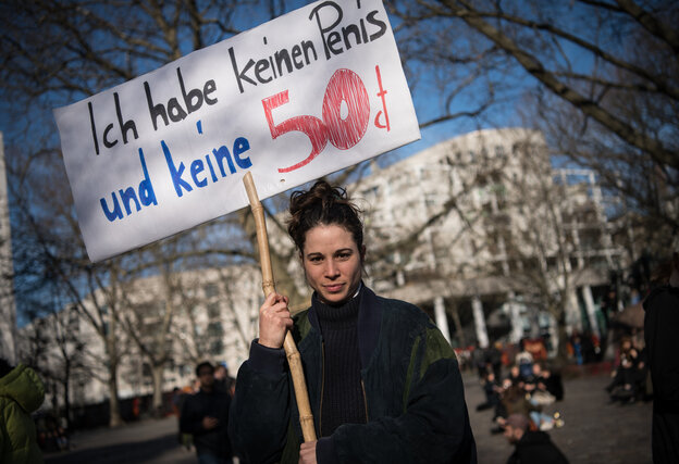 Frau hält ein Schild mit der Aufschrift "Ich habe keinen Penis und keine 50 Cent"