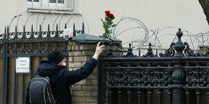 Mann legt Blumen an den Stacheldrahtzahn der ukrainischen Botschaft in Moskau ab
