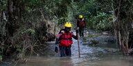 Zwei mit Rettungswesten bekleidete Männer laufen durch über-Knie-hohes Wasser
