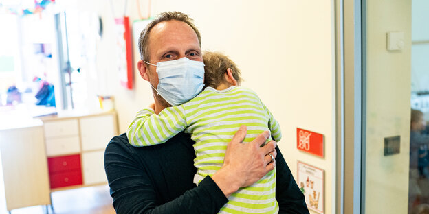 Marco Lemke, Leiter der Kita im Heinrichs-Familienhaus, hält ein Kind in den Armen.
