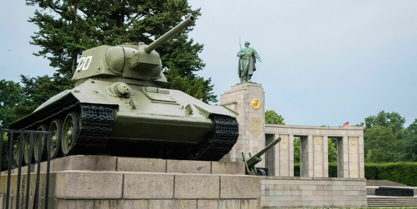 Das Bild zeigt einen der beiden Panzer am sowjetischen Ehrenmal an der Straẞe des 17. Juni, über den eine ukrainische Flagge ausgebreitet ist, die Polizisten gerade entfernen.