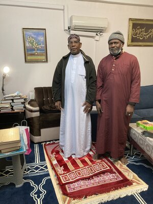 Zwei muslimisch gekleidete Männer stehen auf Gebetsteppichen