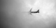 Ein Flugzeug verschwindet hinter grauen Wolken.