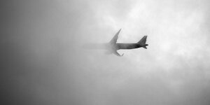 Ein Flugzeug verschwindet hinter grauen Wolken.