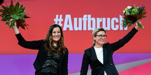 Janine Wissler und Susanne Hennig-Wellsow halten Blumensträuße in die Luft