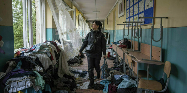 Eine Frau läuft den Flur einer zerstörten Schule entlang