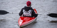 Ein Aktivist im Kanu und der Aufschrift "Frack off" auf dem Rücken