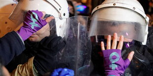 Hände, die Handschuhe mit einem Frauenzeichen tragen und visiere von Polizeihelmen