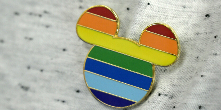 Eine regenbogenfarbige Anstecknadel in Micky-Maus-Form