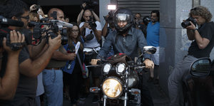 Gianis Varoufakis fährt Motorrad und ist von Journalisten umringt