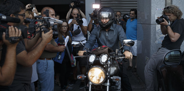 Gianis Varoufakis fährt Motorrad und ist von Journalisten umringt