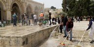 Palästinenser reinigen den Platz auf dem Tempelberg nach Zusammenstößen mit der israelischen Polizei
