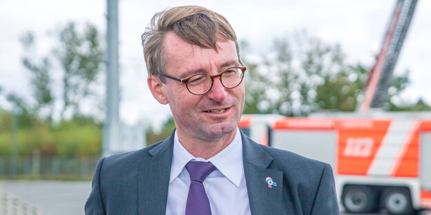 Roland Wöller im Anzug mit Krawatte sieht leicht lächelnd zur Seite.