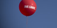 Ein roter Luftballon mit dem Parteilogo "Die Linke" fliegt vor einem blauen Himmel