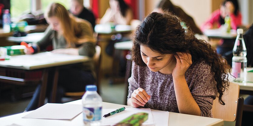 Schülerin sitzt im Klassenraum an einer schriftlichen Arbeit