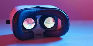 Eine VR-Brille liegt auf einem Tisch, angeleuchtet in pink-blauen Licht