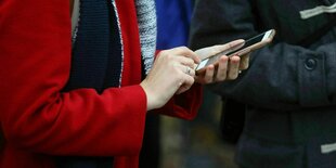 Eine junge Frau hält ihr Handy in der Hand