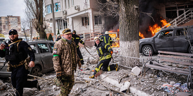 Feuerwehrmänner und Militärs bei Rettungsarbeiten nach dem Raketeneinschlag in eine Wohnhaus