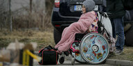 Ein Kind im Rollstuhl vor einem Auto