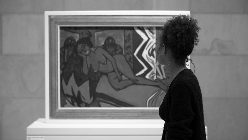 Schwarz-Weiß-Videostill einer Frau, der Medienkünstlerin Natasha Kelly, in Silhouette vor dem Gemälde "Schlafende Milli" in der Kunsthalle Bremen.