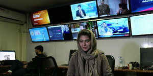 Frau mit Kopftuch im Fernsehstudio vor Bildschirmen