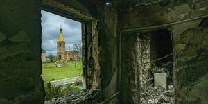 Zerstörtes Haus mit Blick aus dem Fenster auf eine Kirche