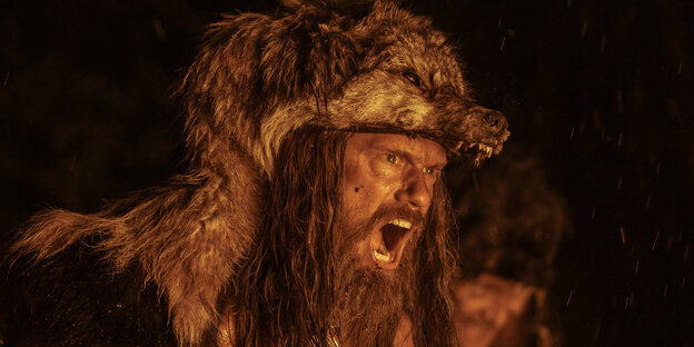 Amleth (Alexander Skarsgård) fletscht im Wolfsfell bei Feuerschein die Zähne.