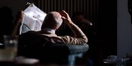 Ein Mann liest eine Zeitung in einem Café