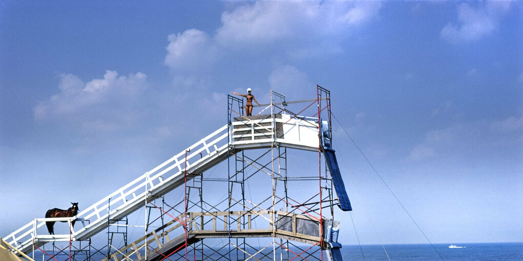 Sprungturm am Meer, auf dem gerade ein Pferd hochläuft