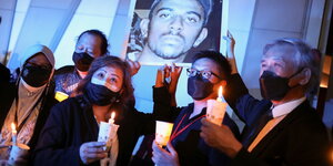 Menschen mit Kerzen halten ein Porträt des zu Tode verurteilten