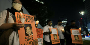 Aktivisten halten orange Schilder mit dem Porträt von Nagaenthran