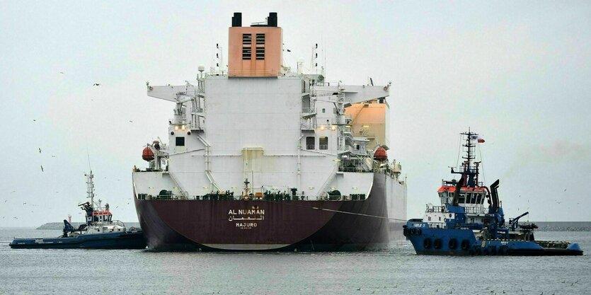 Ein Gastanker wird von Beibooten in den Hafen gelotst